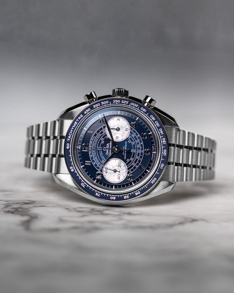 OMEGA Speedmaster Chronoscope mit blauem Zifferblatt am Edelstahlband auf der Seite liegend vor grauem Hintergrund