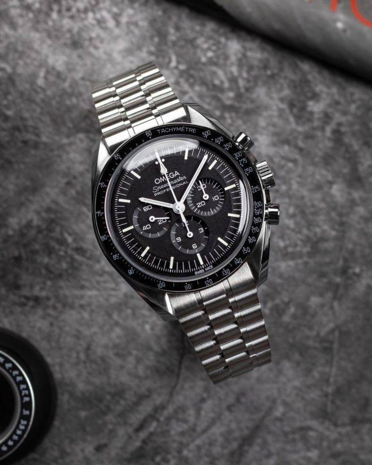 OMEGA Speedmaster Moonwatch Professional am Edelstahlband stehend vor grauem Hintergrund