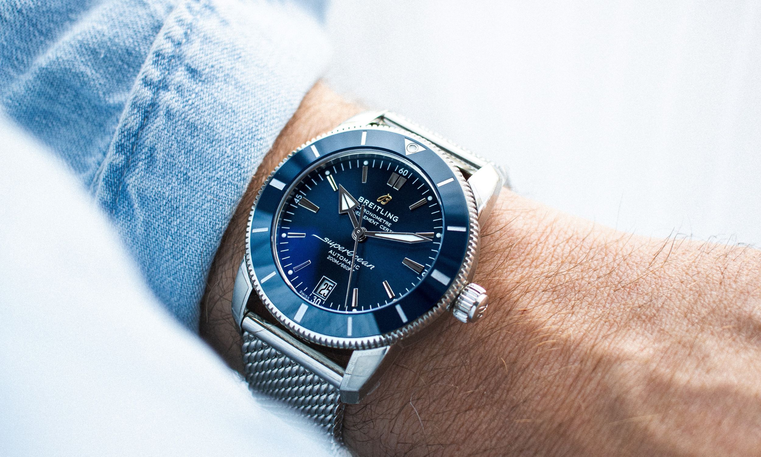 Die Breitling Superocean Heritage in blau abgebildet an einem Handgelenk vor weißem Hintergrund