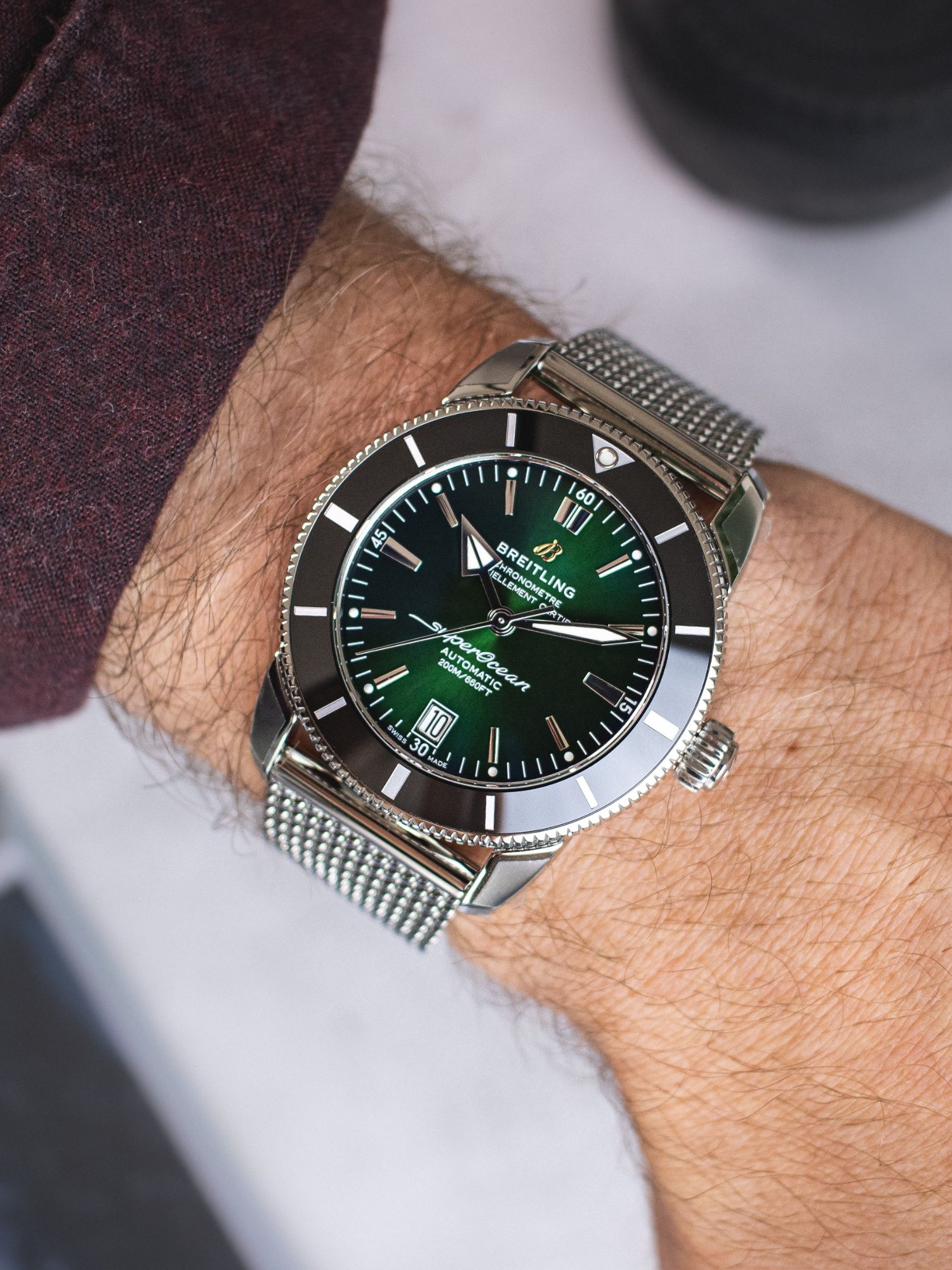 Breitling Superocean Heritage in grün am Handgelenk vor weißem Hintergrund