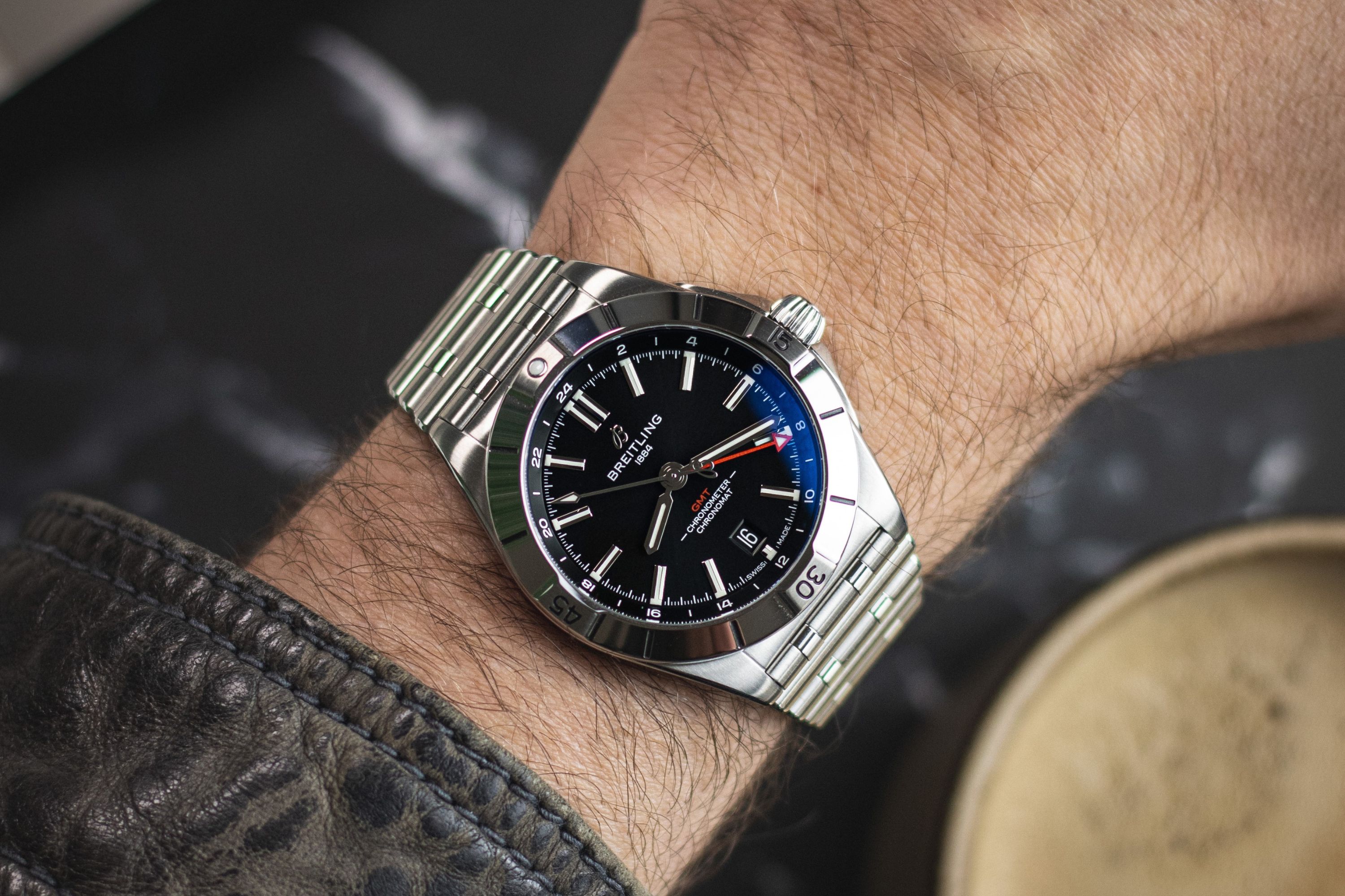 Die Breitling Chronomat GMT mit schwarzem Zifferblatt abgebildet an einem Handgelenk vor dunklem Hintergrund