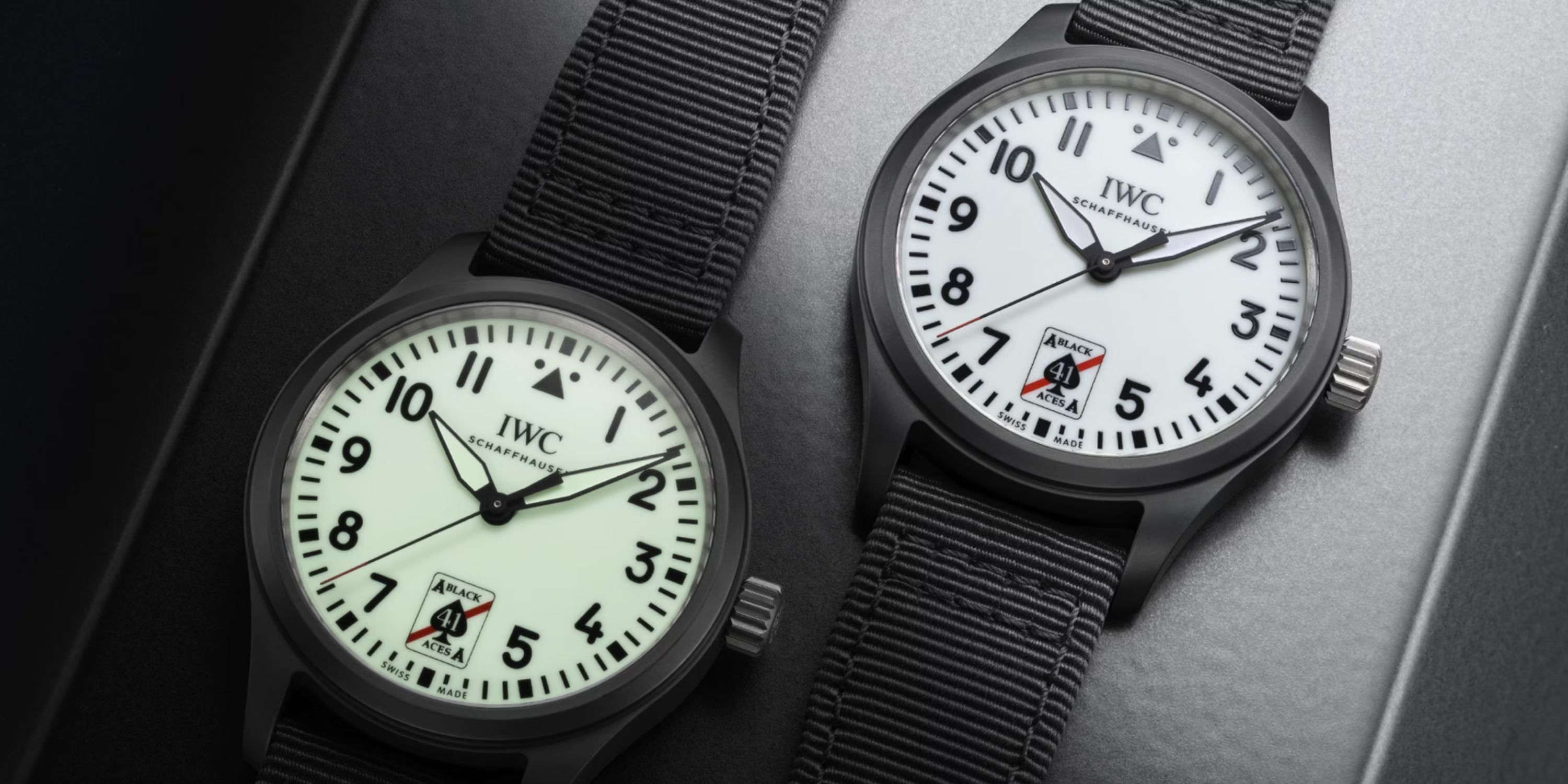 2 Modelle der IWC Pilot’s Watch 41 Black Aces nebeneinander liegend am schwarzen Textilarmband