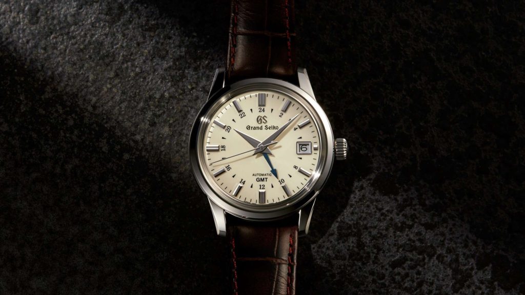 Grand Seiko SBGM221 mit elfenbeinfarbenem Zifferblatt an einem dunklen Lederarmband abgebildet vor schwarzem Hintergrund
