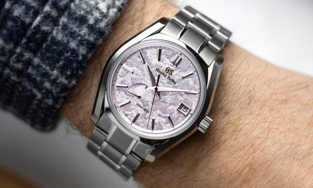 Grand Seiko Shunbun Referenz SBGA413 mit pinkem Zifferblatt am Edelstahlarmband an einem Handgelenk getragen vor hellem Hintergrund