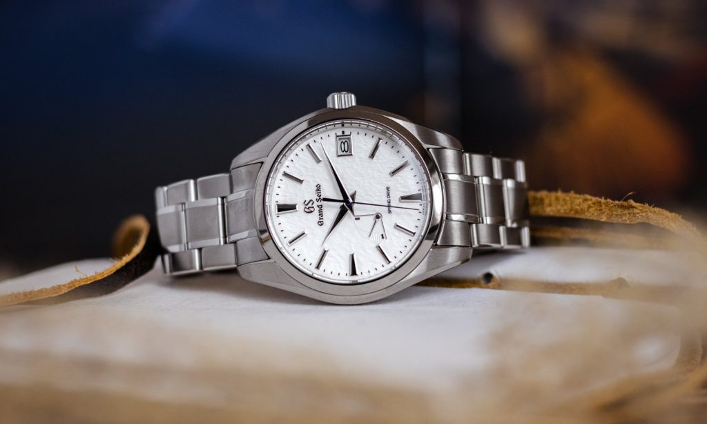 Grand Seiko Snowflake Referenz SBGA211 mit weißem Zifferblatt am Edelstahlarmband auf der Seite liegend