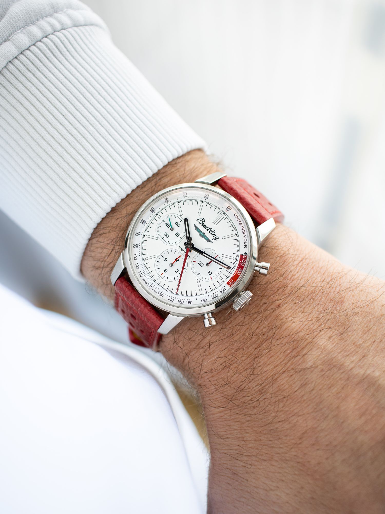 Wristshot der Breitling Top Time Thunderbird in Weiß am roten Lederarmband
