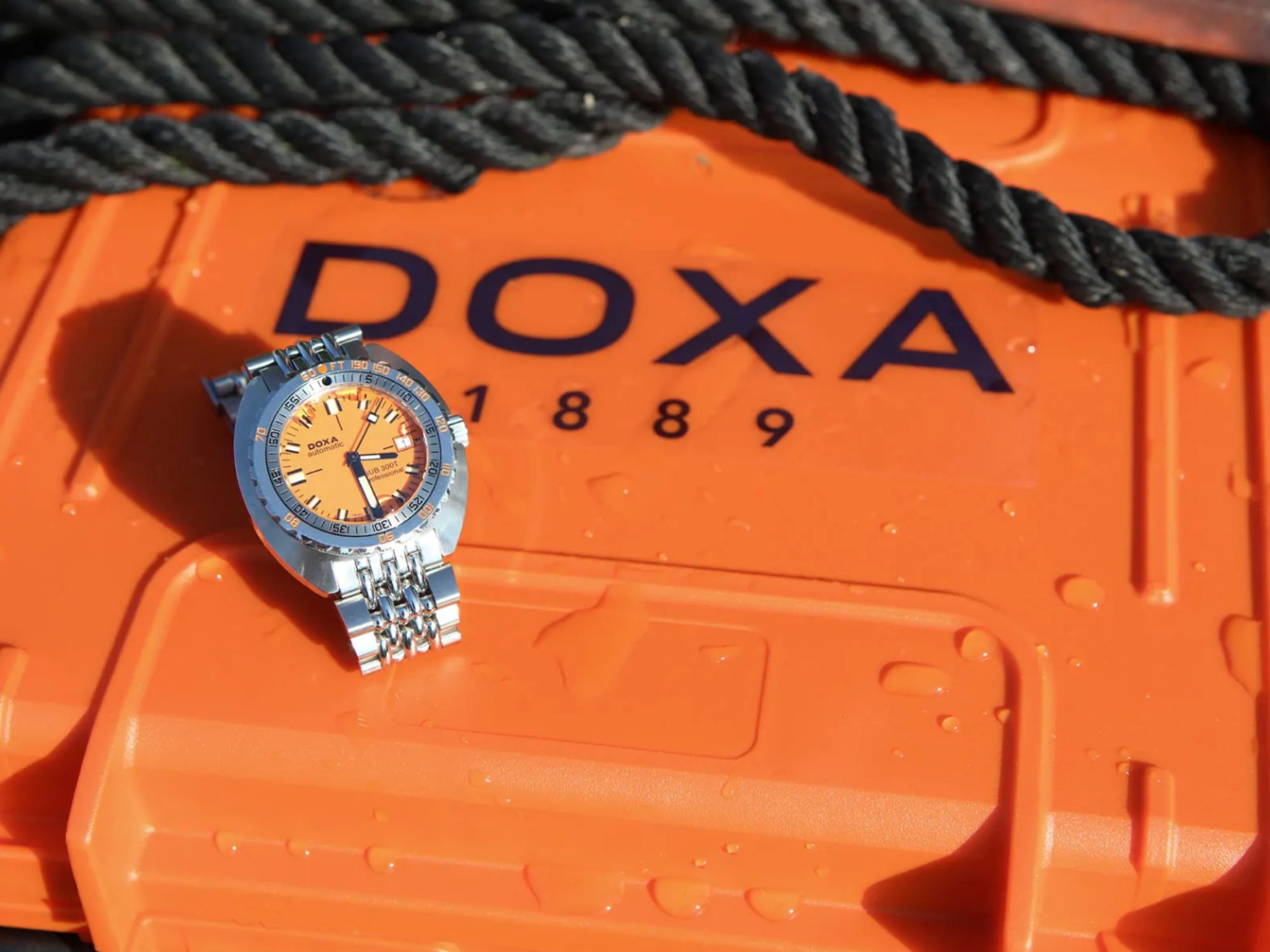 Orangene Doxa Uhr auf orangenem Koffer mit "Doxa" Schriftzug und einem schwarzen Seil