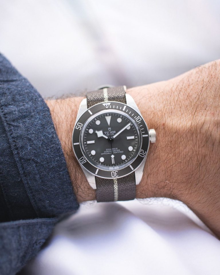 Tudor Black Bay 58 925 abgebildet an einem Handgelenk mit blauem Ärmel vor hellem Hintergrund