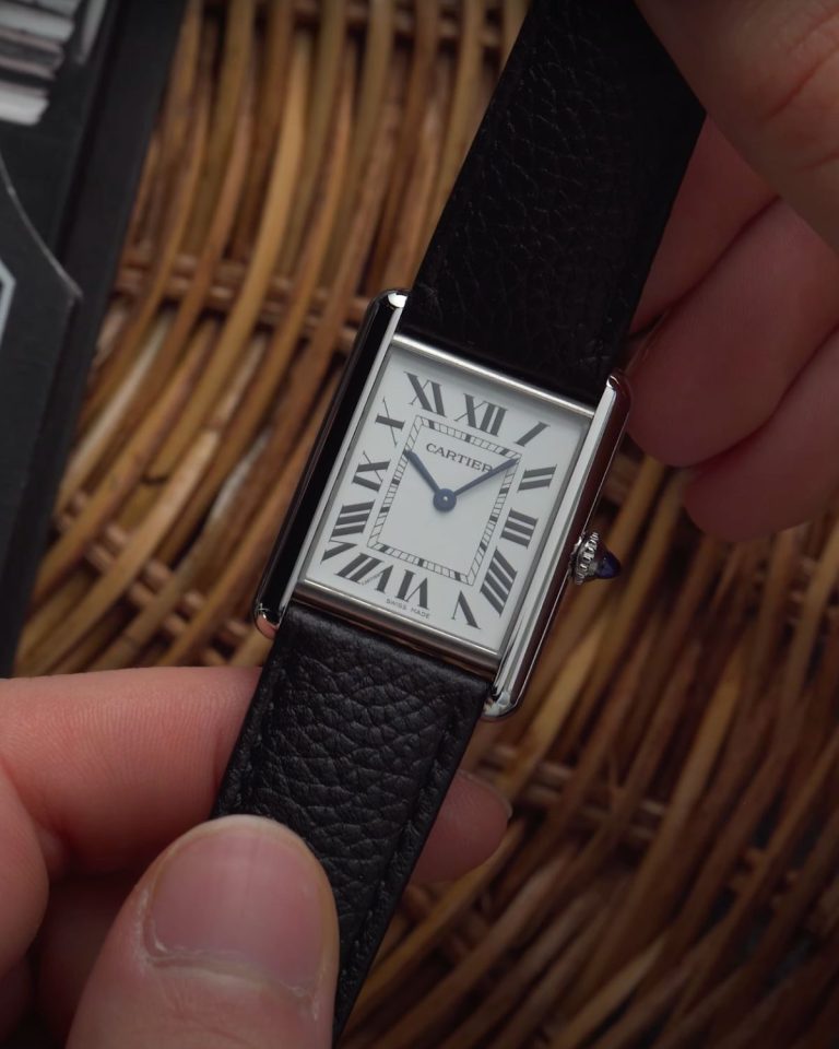 Cartier Tank Must am Lederband in der Hand gehalten