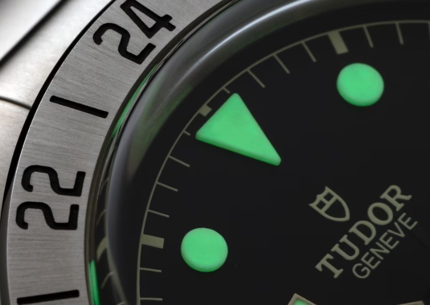 Nahaufnahme des schwarzen Zifferblattes der Tudor Black Bay Pro mit grün leuchtenden Stundenindizes