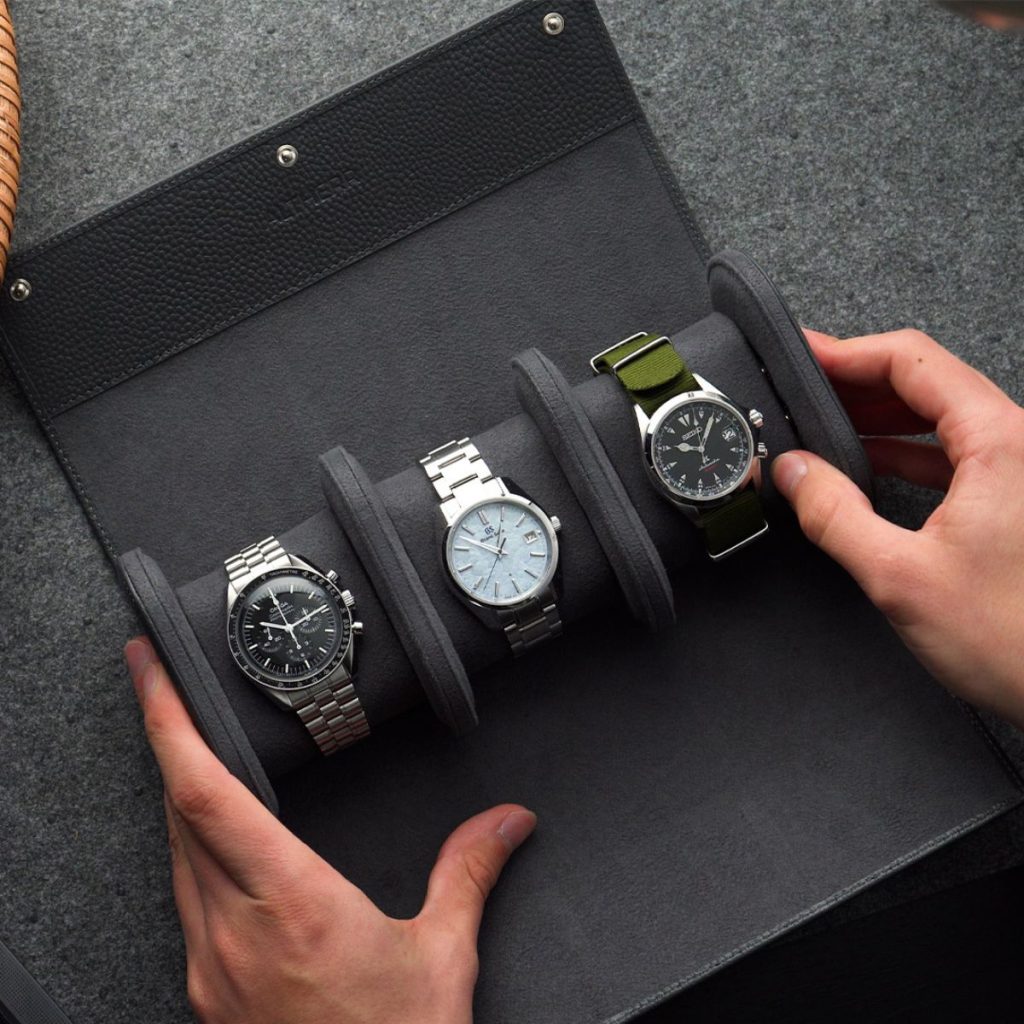 Uhrensammlung in schwarzer Uhrenrolle auf grauem Hintergrund
