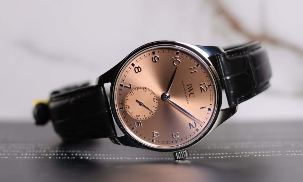 IWC Portugieser Automatic 40 mit rosafarbenem Zifferblatt am schwarzen Lederarmband auf der Seite liegend