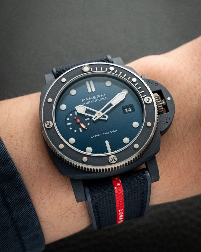 Panerai Submersible QuarantaQuattro Luna Rossa Ti-Ceramitech mit blauem Gehäuse, Zifferblatt und Armband vor grauem Hintergrund