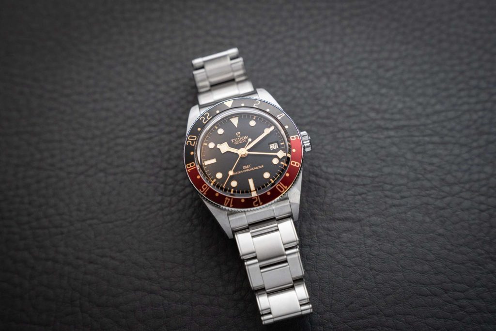 TUDOR Black Bay 58 GMT am Edelstahlarmband liegend auf einem schwarzen Untergrund mit Struktur