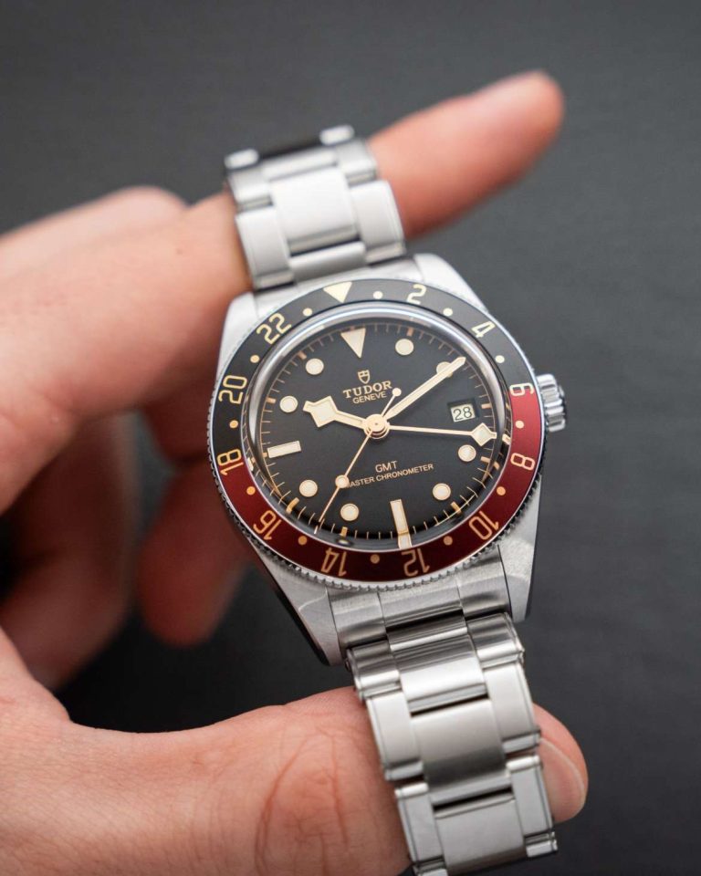 TUDOR Black Bay 58 GMT am Edelstahlarmband gehalten von einer Hand vor dunklem Hintergrund