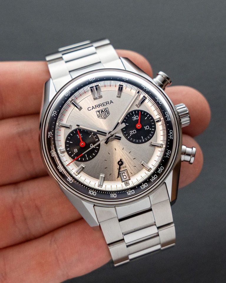 Nahaufnahme des TAG Heuer Carrera Glassbox Panda Chronograph am Stahlband vor grauem Hintergrund