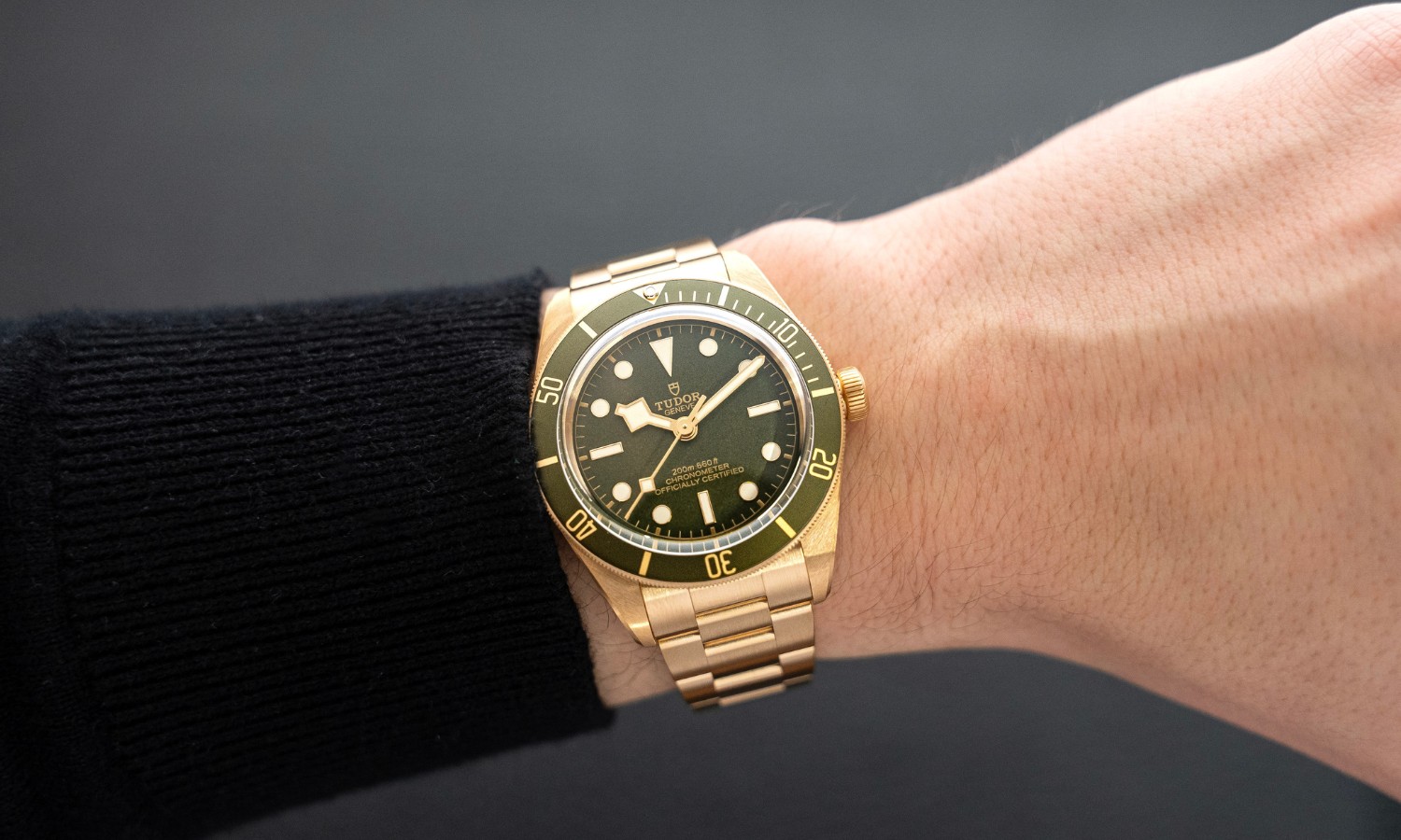 TUDOR Black Bay 58 18k Gold an einem Handgelenk vor grauem Hintergrund