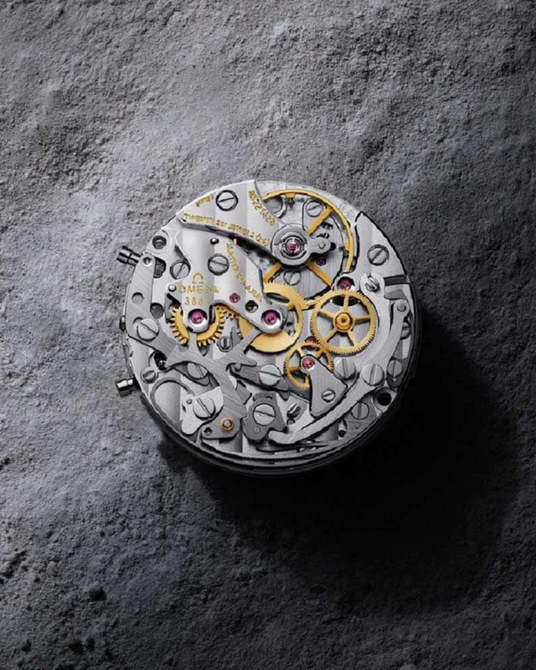 Master Chronometer Uhrwerk der OMEGA Speedmaster Moonwatch vor einer grauen Mondoberfläche