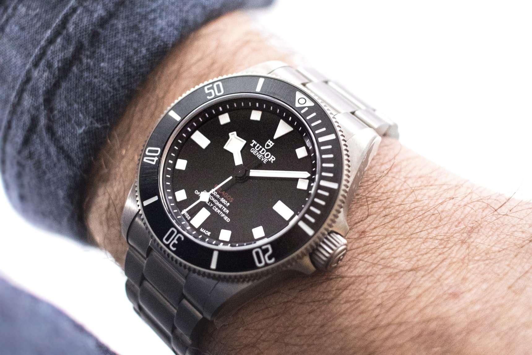 Tudor Pelagos 39 abgebildet an einem Handgelenk mit blauem Ärmel vor hellem Hintergrund