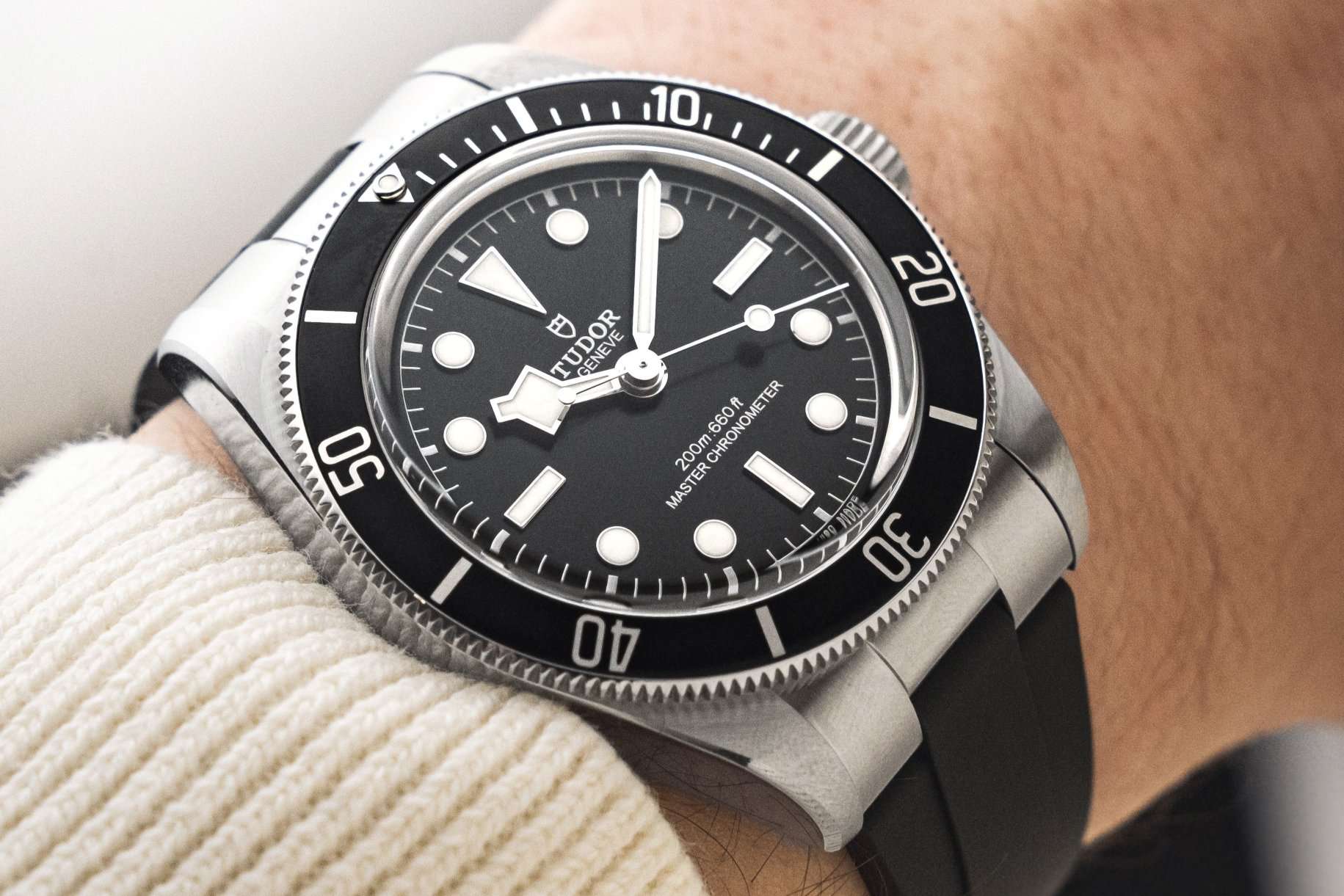 TUDOR Black Bay 41 METAS am schwarzen Kautschukarmband, schwarzem Zifferblatt und schwarzer Lünette abgebildet an einem Handgelenk mit weißem Ärmel