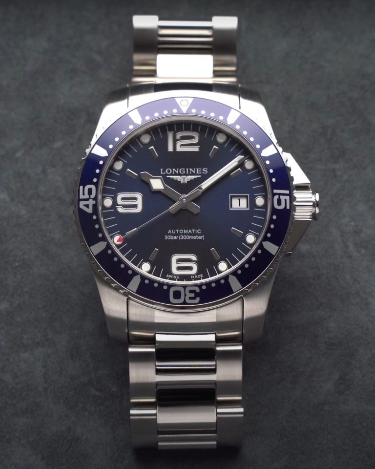 Nahaufnahme der Longines HydroConquest 41 mit blauem Zifferblatt vor grauem Hintergrund liegend