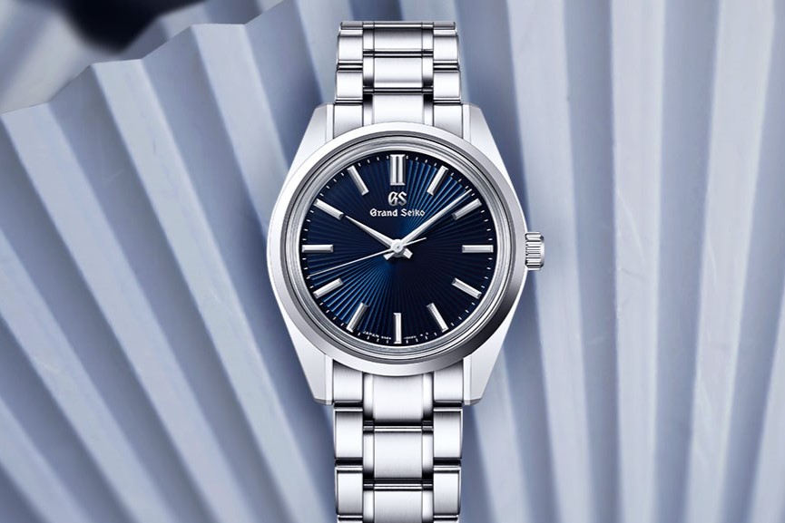 Grand Seiko SBGW299 mit strukturiertem blauem Ziifferblatt vor hellblauem strukturiertem Hintergrund