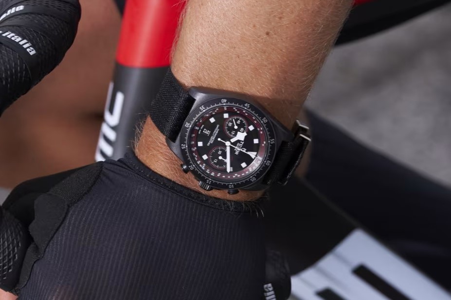 Tudor Pelagos FXD Chronograph in der Cycling Edition mit schwarzem Zifferblatt, schwarzem Gehäuse und schwarzem Armband abgebildet am Handgelenk eines Radsportlers, der sein Lenkrad in den Händen hält