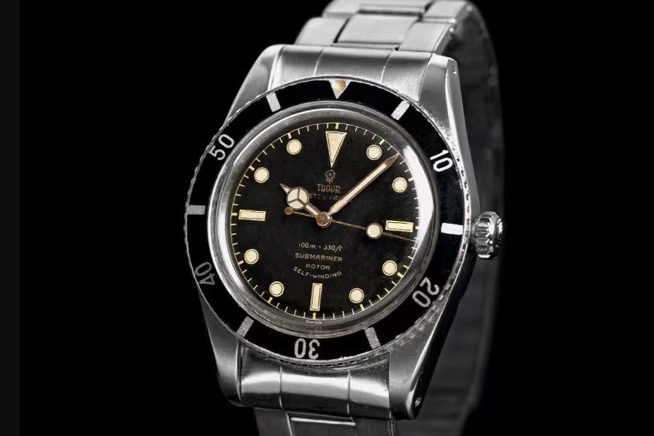 Tudor Submariner aus 1954 mit schwarzem Zifferblatt, schwarzer Lünette und Edelstahlarmband vor schwarzem Hintergrund