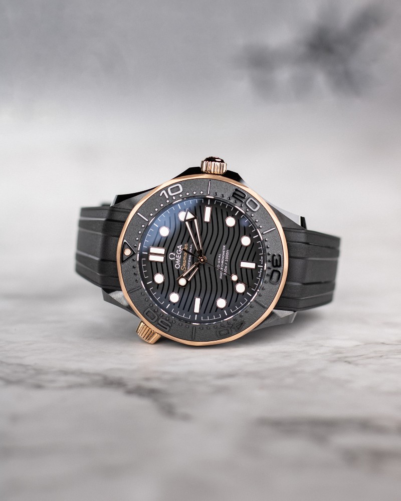 OMEGA Seamaster Diver 300M Sedna Gold auf der Seite liegend vor hellgrauem Hintergrund