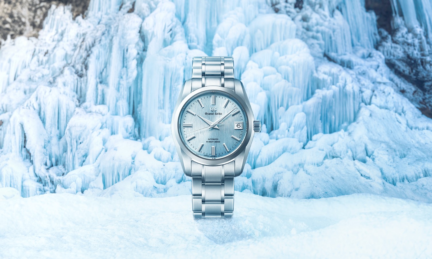 Grand Seiko SBGH347 mit eisblauem Zifferblatt stehend vor eisblauem Hintergrund