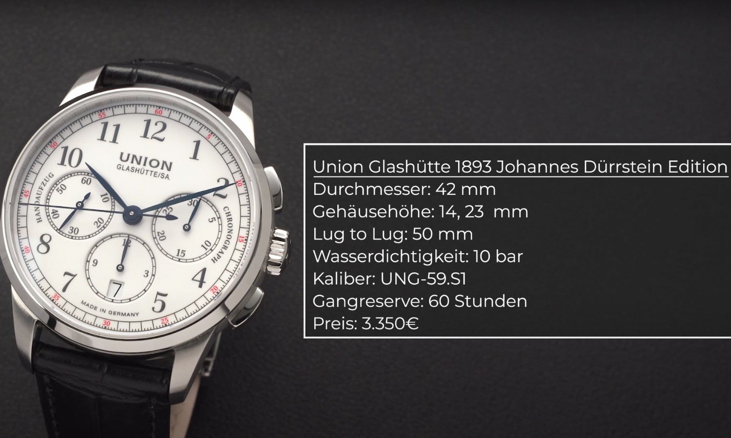 Der Union Glashütte 1893 Johannes Dürrstein Chronograph mit weißem Zifferblatt am Lederarmband stehend vor dunkelgrauem Hintergrund