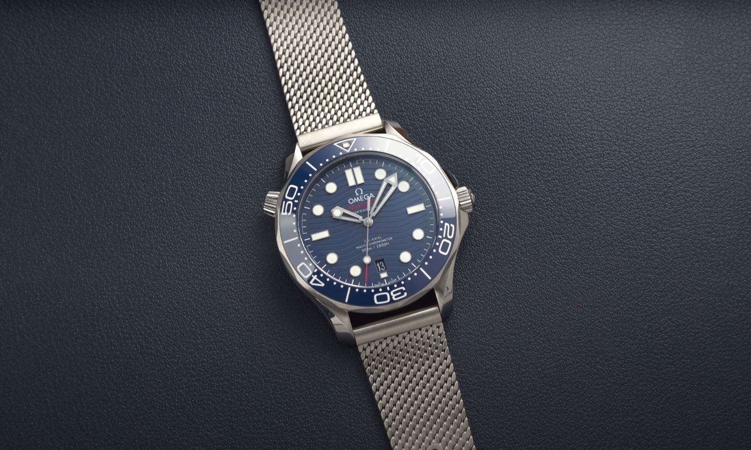 Die OMEGA Seamaster Diver 300M mit blauem Zifferblatt am Edelstahlarmband liegend vor dunkelblauem Hintergrund