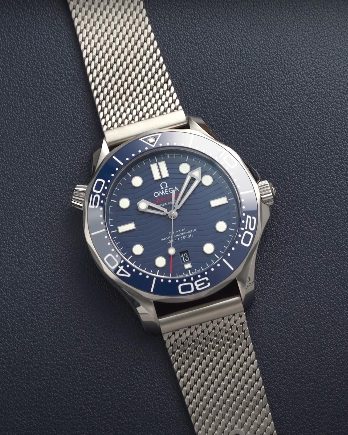 Die OMEGA Seamaster Diver 300M mit blauem Zifferblatt am Edelstahlarmband liegend vor dunkelblauem Hintergrund