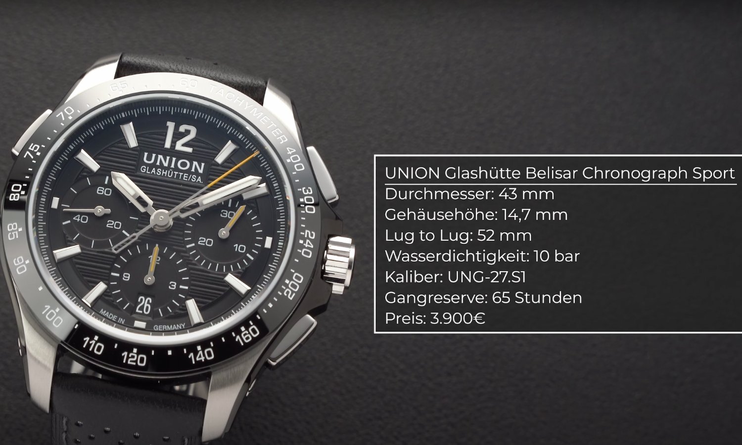 Die UNION Glashütte Belisar Chronograph Sport mit schwarzem Zifferblatt am schwarzen Lederarmband stehend vor dunkelgrauem Hintergrund