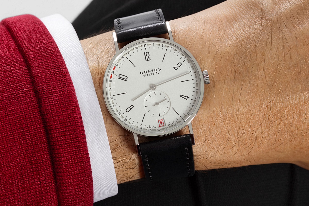 Blick auf der die NOMOS Tangente 2date mit weißem Zifferblatt auf dem Handgelenk eines Mannes.