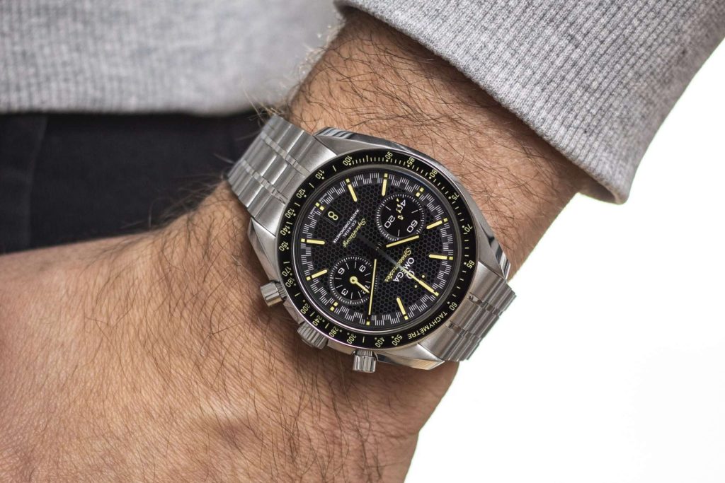 Omega Speedmaster Super Racing abgebildet an einem Handgelenk mit grauem Ärmel vor weißem Hintergrund