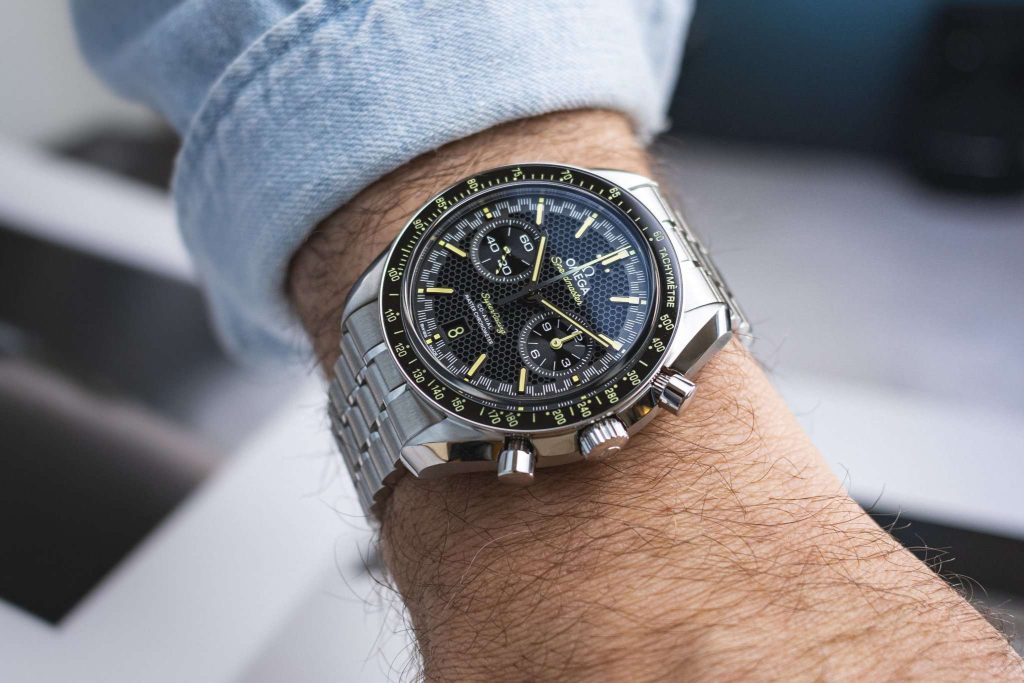 Omega Speedmaster Super Racing abgebildet an einem Handgelenk mit hellblauem Ärmel vor weißschwarzem Hintergrund