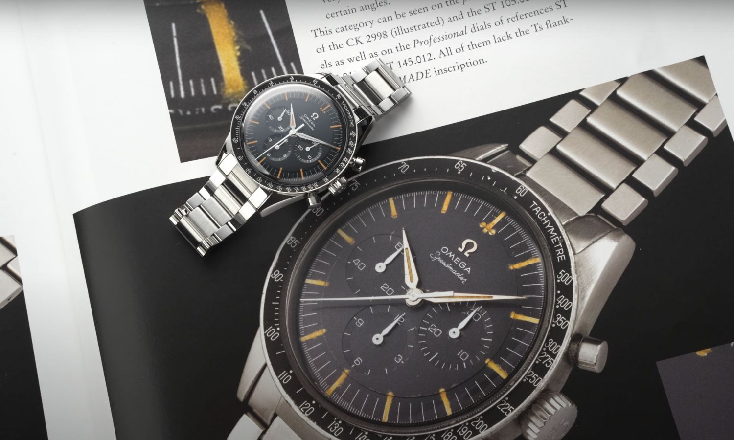 Die OMEGA Speedmaster First OMEGA in Space mit dunkelblauem Zifferblatt am Edelstahlarmband liegend auf einem OMEGA Buch mit Bild der originalen Uhr