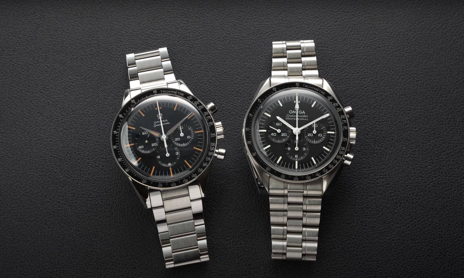 Die OMEGA Speedmaster First OMEGA in Space links und die OMEGA Speedmaster Professional Moonwatch rechts liegend vor schwarzem Hintergrund