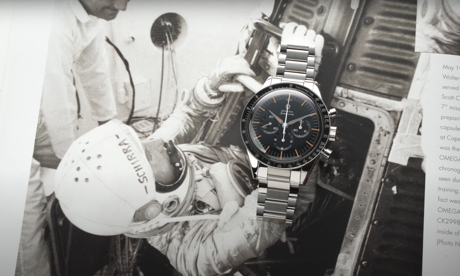 Die OMEGA Speedmaster First OMEGA in Space mit dunkelblauem Zifferblatt am Edelstahlarmband liegend auf einem OMEGA Buch mit Bild eines Astronauten