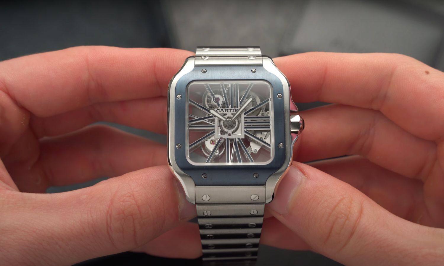 Die Cartier Santos Skeleton mit skelettiertem Zifferblatt am Edelstahlarmband in zwei Händen gehalten