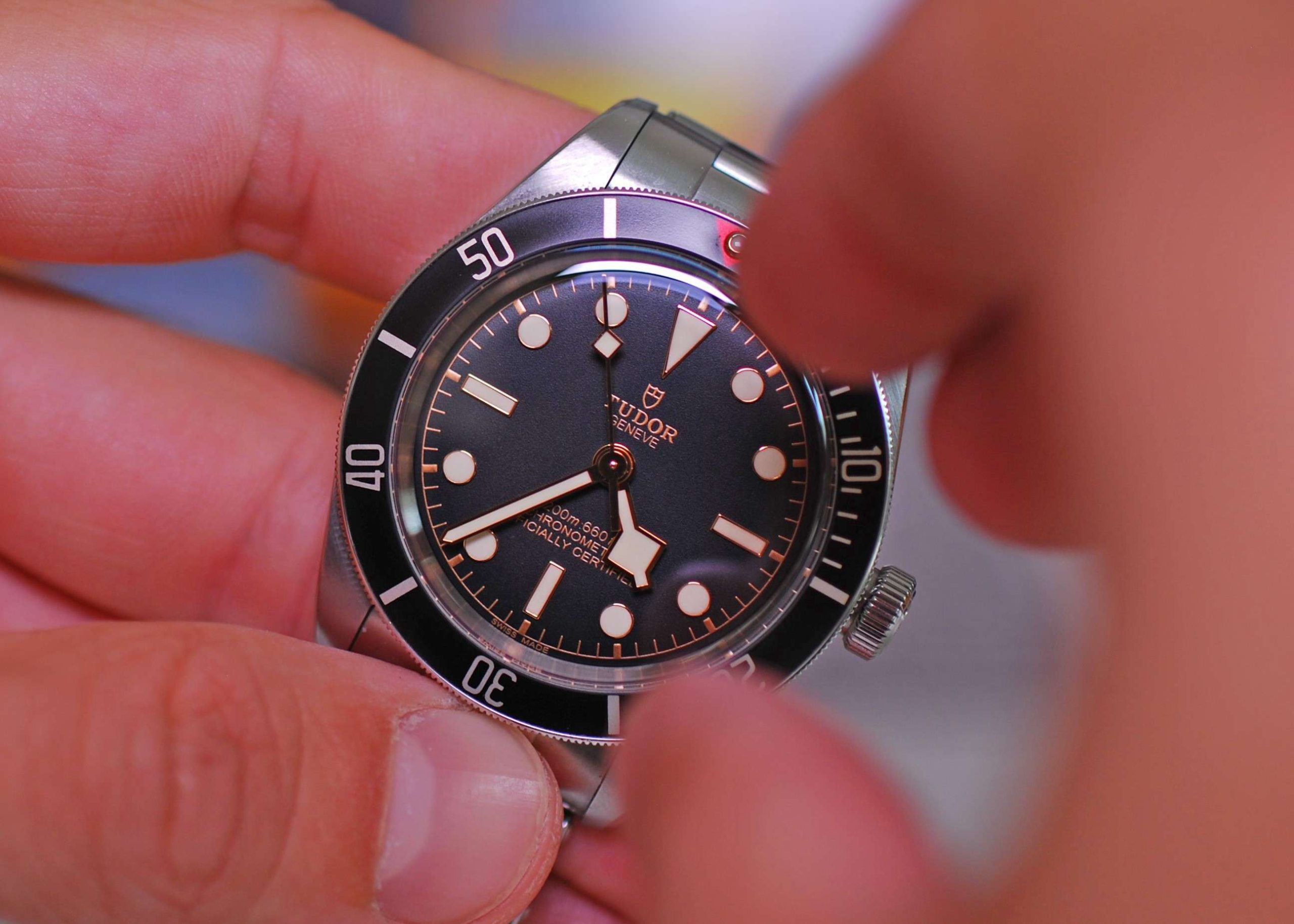 Tudor Black Bay 58 mit schwarzem Zifferblatt und schwarzer Lünette am Edelstahlarmband gehalten von zwei Händen vor hellem Hintergrund