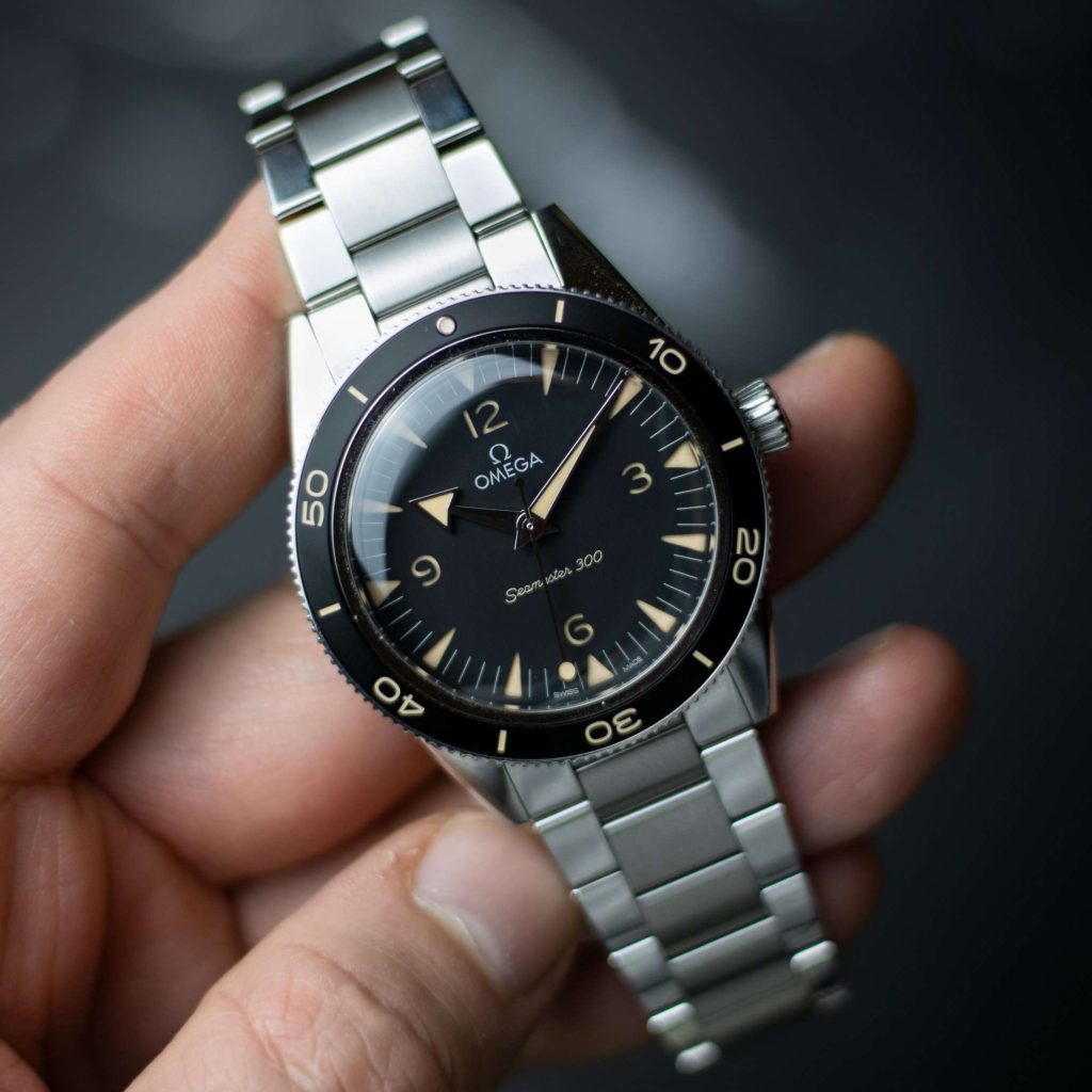 Omega Seamaster 300 mit schwarzem Zifferblatt am Edelstahlarmband gehalten von einer Hand vor dunklem Hintergrund