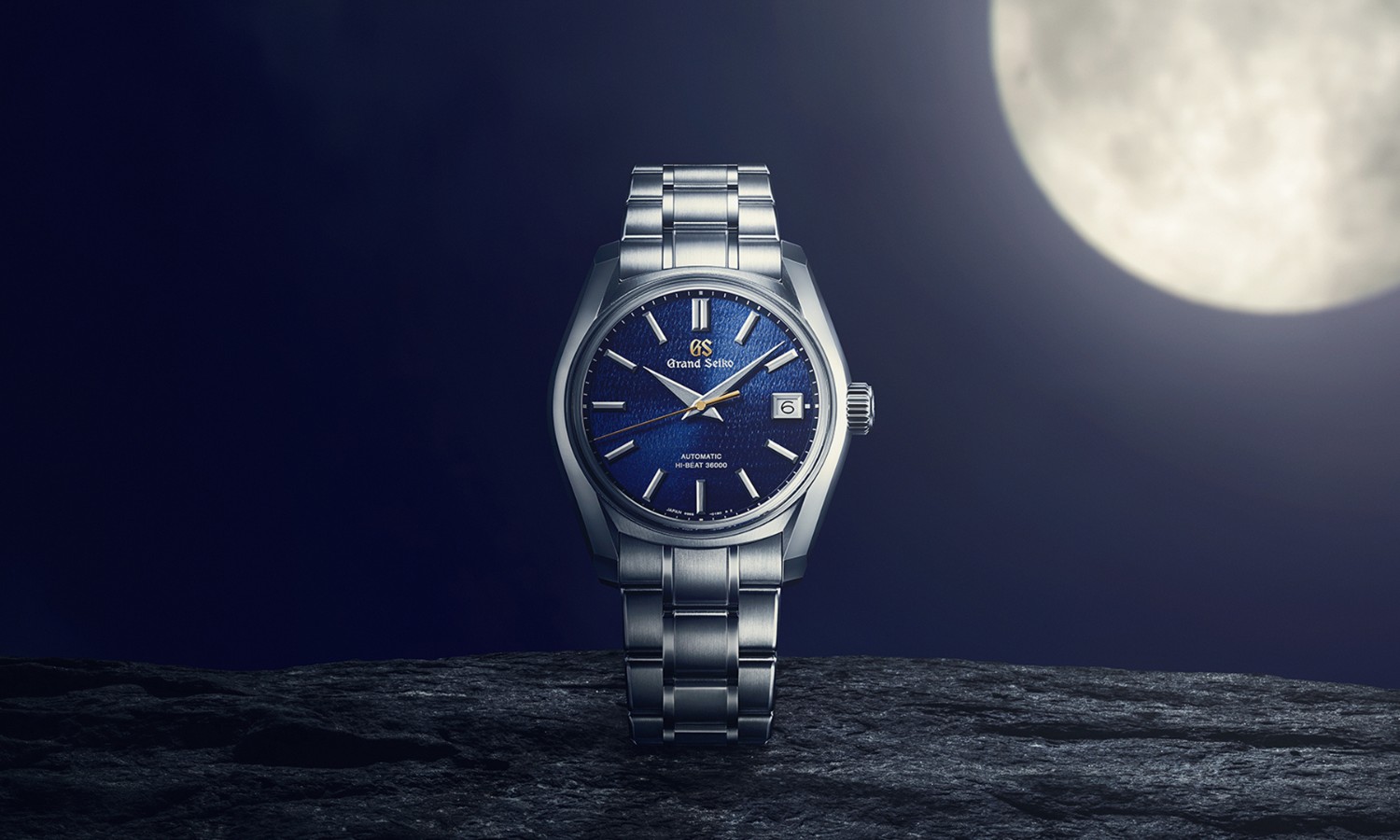 Grand Seiko SBGH353 Shubun mit dunkelblauem Zifferblatt am Edelstahlarmband stehend vor dunklem Nachthimmel mit leuchtendem Mond oben rechts