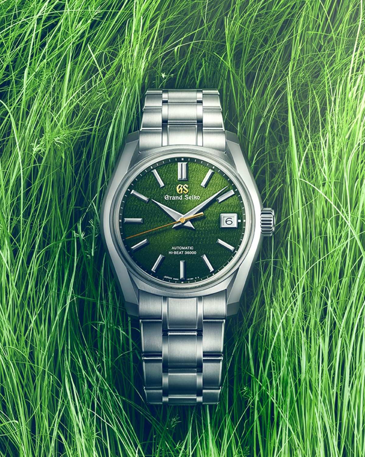 Grand Seiko SBGH351 Rikka mit grünem Zifferblatt am Edelstahlarmband stehend vor grünem Gras