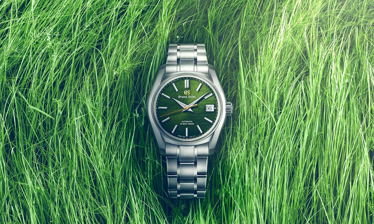 Grand Seiko SBGH351 Rikka mit grünem Zifferblatt am Edelstahlarmband stehend vor grünem Gras