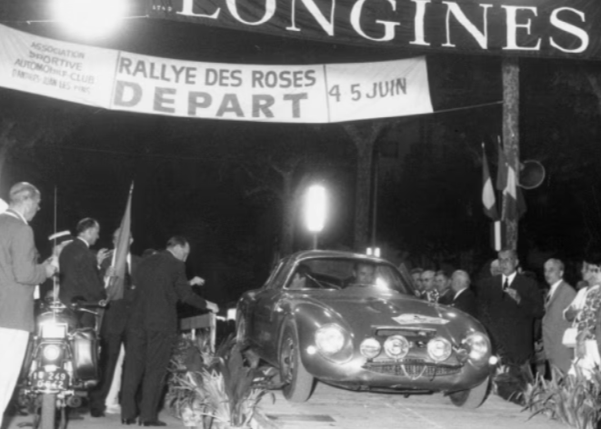 Schwarzweiß-Foto eines Rallye-Wagens der vor Publikum die Ziellinie durchfährt. Darüber hängt ein Banner mit dem Longines-Schriftzug