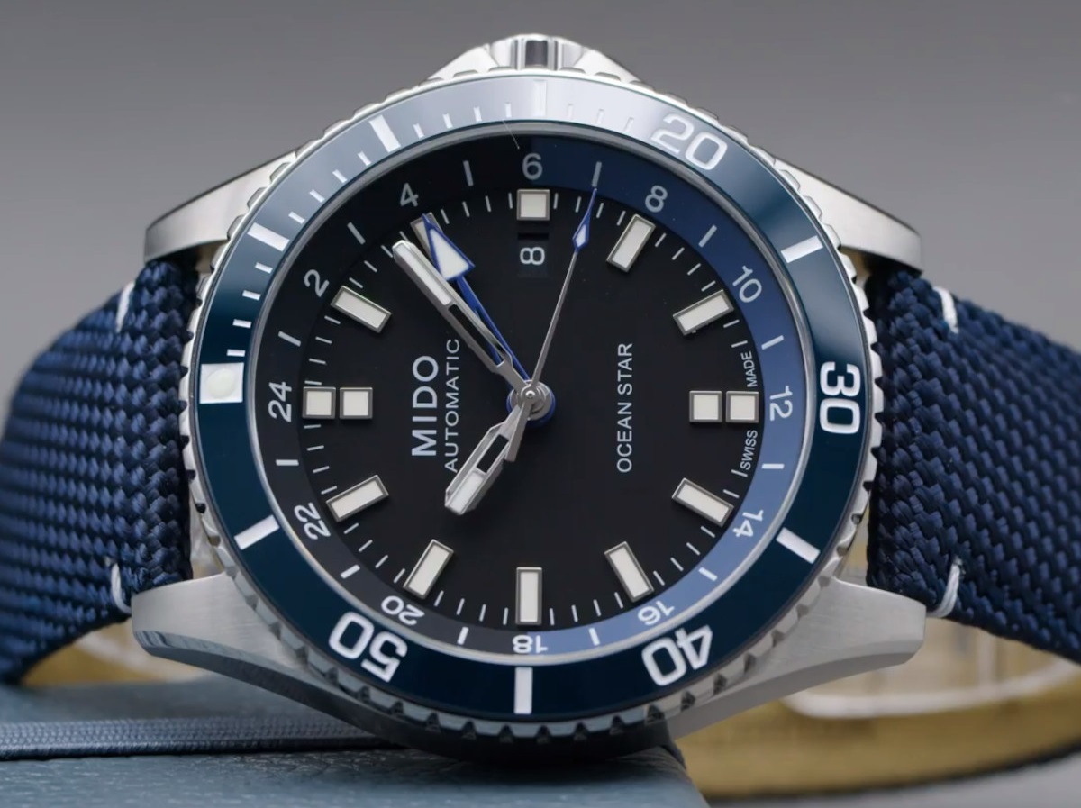 Seitliche Nahaufnahme der MIDO OCean Star GMT mit schwarzem Zifferblatt und einem blauen Nylon-Band.