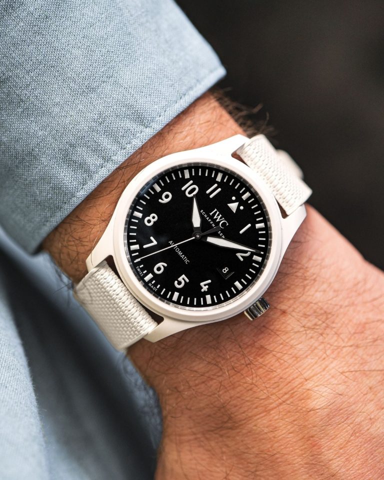 IWC Pilot’s Watch Automatic 41 TOP GUN „Lake Tahoe“ mit schwarzem Zifferblatt am weißen Kautschukarmband an einem Handgelenk mit hellblauem Ärmel getragen
