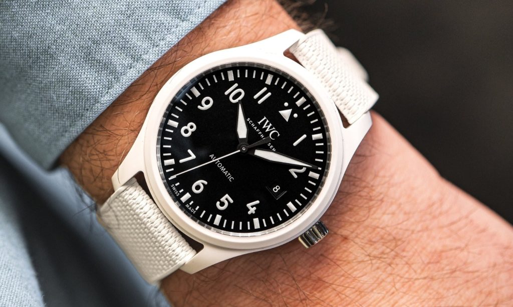 IWC Pilot’s Watch Automatic 41 TOP GUN „Lake Tahoe“ mit schwarzem Zifferblatt am weißen Kautschukarmband an einem Handgelenk mit hellblauem Ärmel getragen